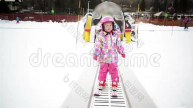 冬季户外运动中的小女孩呆在滑雪传送带上。 孩子开始滑雪了。 度假村快乐滑雪体验。